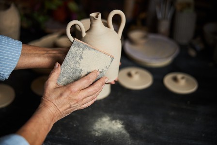 Female potter hands polishing clay pot