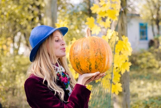 Portrait of women holding and pretending to kiss pumpkin