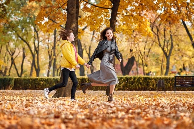 Two happy girls running in autumn city park