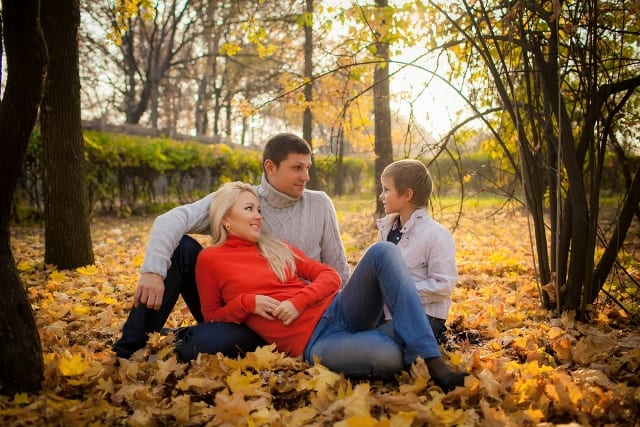 Young family sitting in autumn park