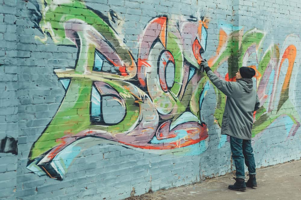 artist painting colorful graffiti using spray paint